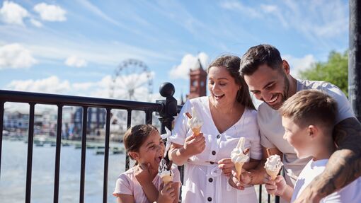 Family eating ice cream in a bay with a Ferris wheel behind