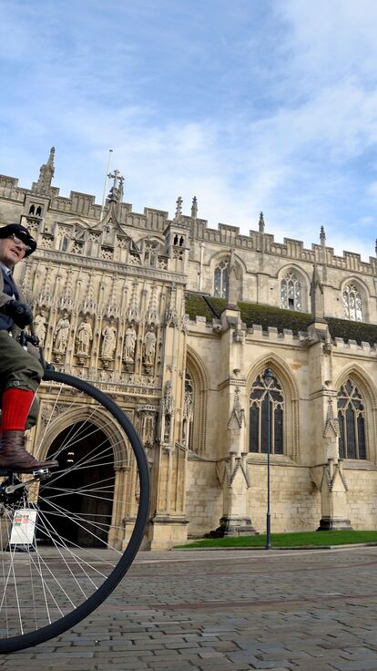 The exterior of Gloucester Cathedral with a man on a penny farthing outside