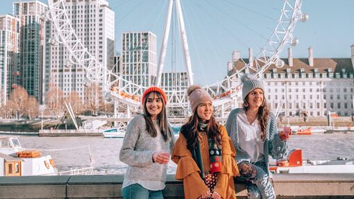 Three women enjoying themselves in London with the London Eye in the background