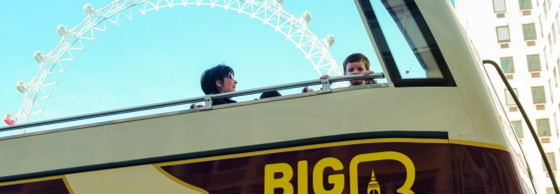 Big Bus London drives by with the London Eye behind in a beautiful blue sky