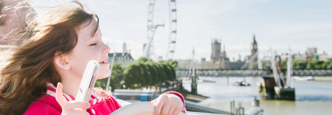 A woman's hair flows in the wind on the Big Bus Tour's top level as the bus crosses over the River Thames