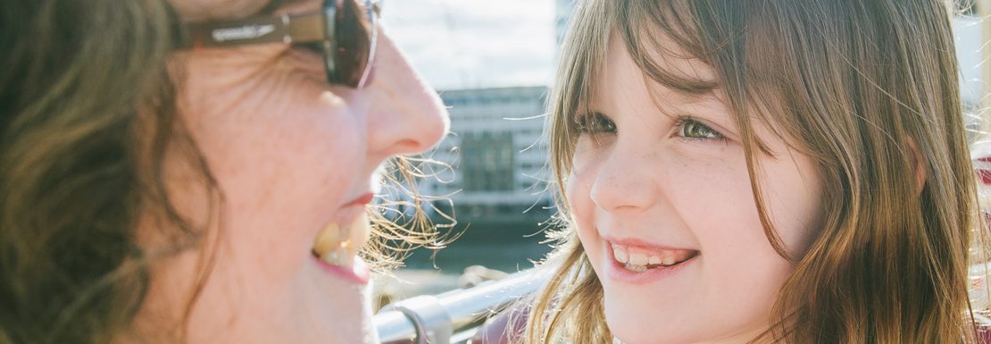 A mother and her young daughter smile on a sunny day from the top deck with the Shard in the background