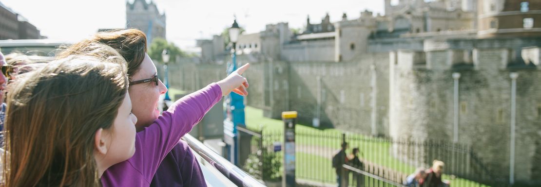 A mother points out to her daughter that they're viewing the Tower of London from the top of the Big Bus Tour