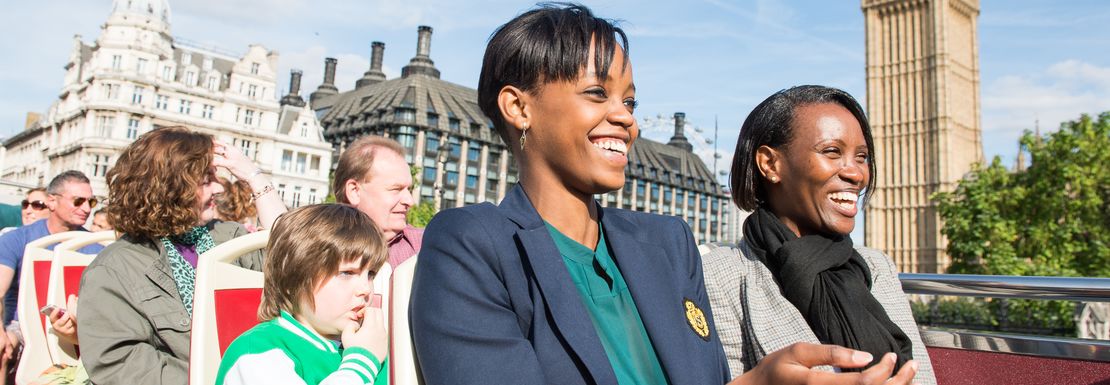 Families enjoy the Big Bus tour and the sun in London as they pass the House of Commons