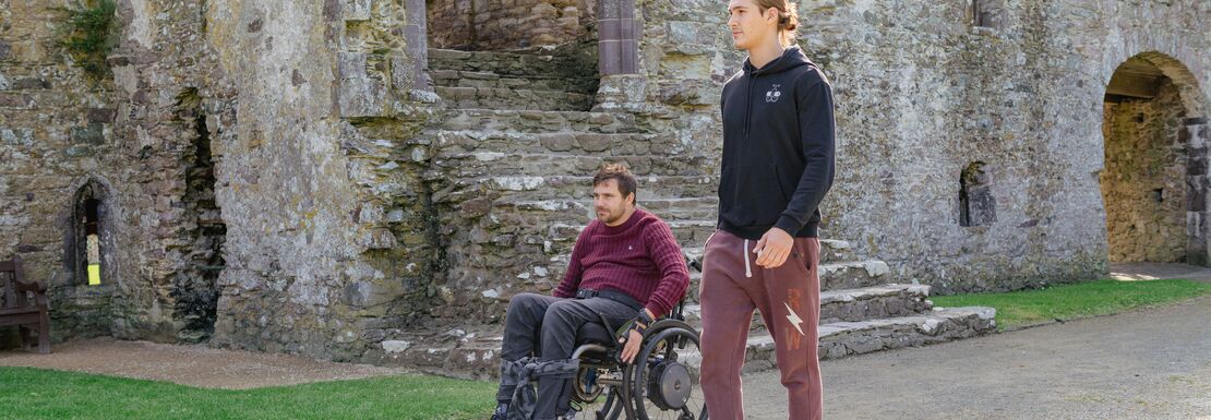 Cadw Explorer Pass - Visitor in a wheelchair with a friend