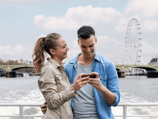 A couple smiling while sailing on the Uber Boat Thames Clipper service