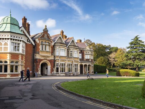 Bletchley Park from the outside with a blue sky and rounded green lawn