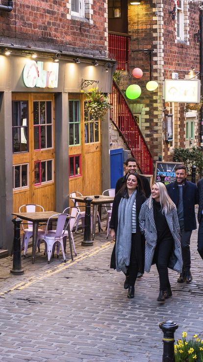 Group of friends walking down cobbled street with dim lights