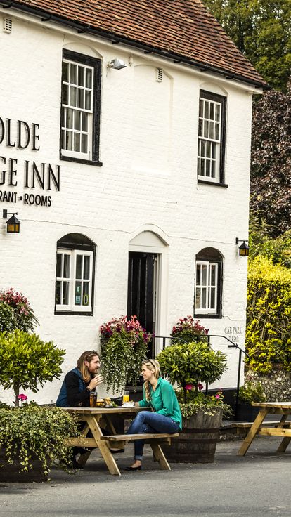 A couple sitting outside the pub on a bench having a drink