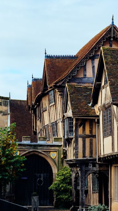 Narrow path beside old buildings leading to black gates