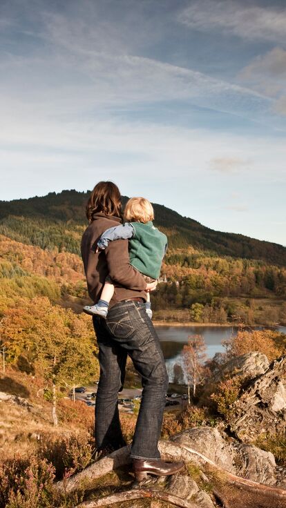 Woman and child standing on a hilltop overlooking a lake