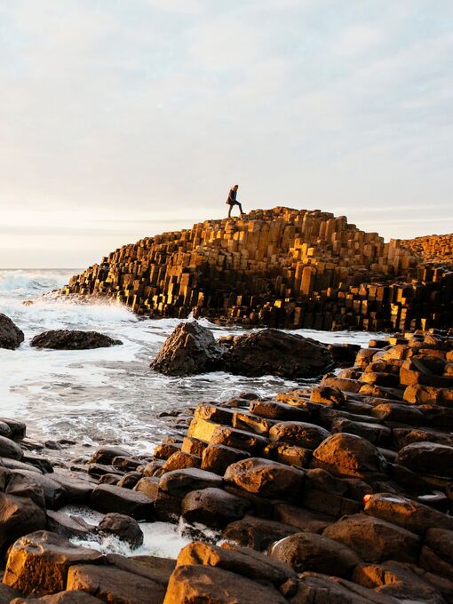 Man standing on rock formations in the sea