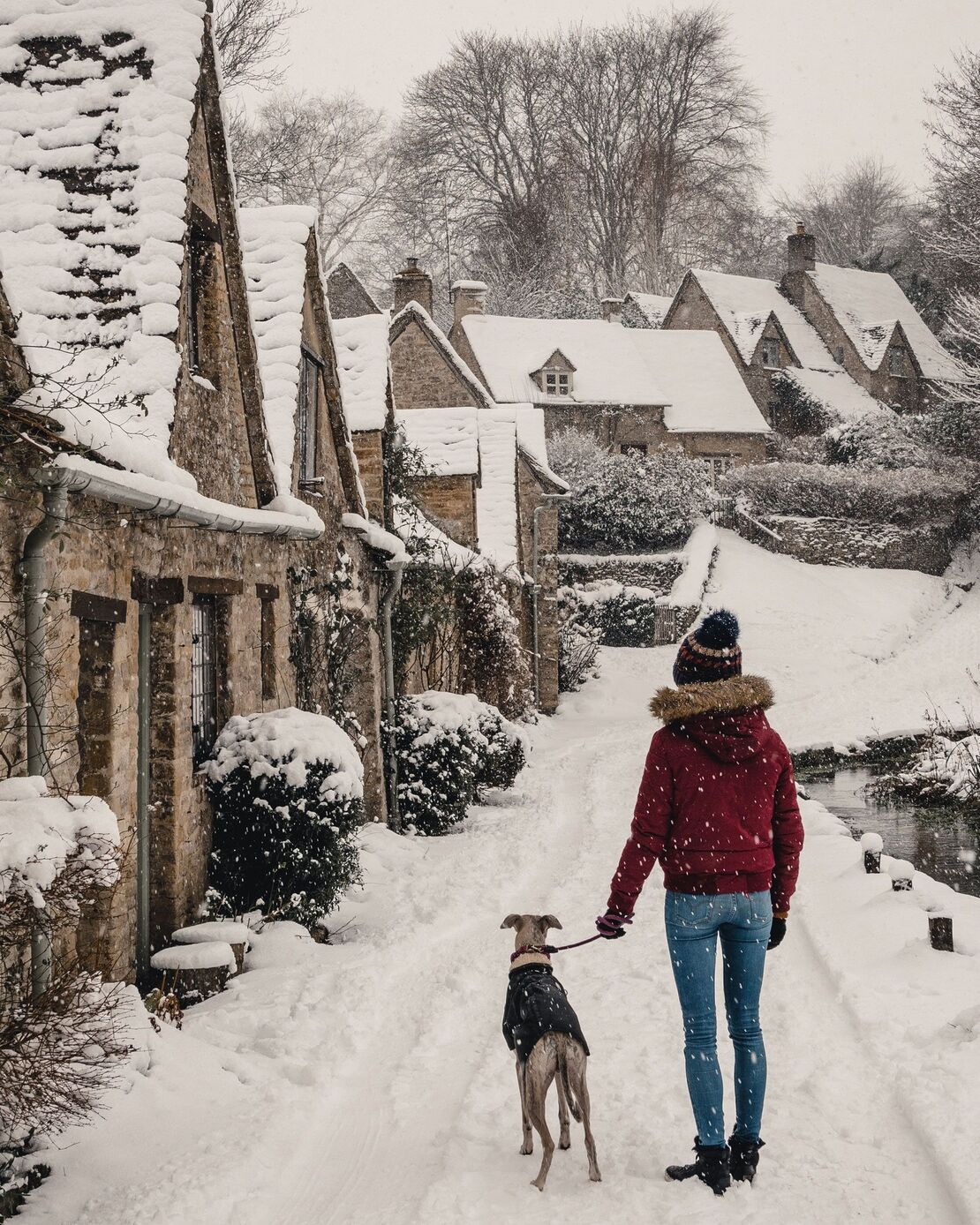 A snowy village in Britain with a dog walker
