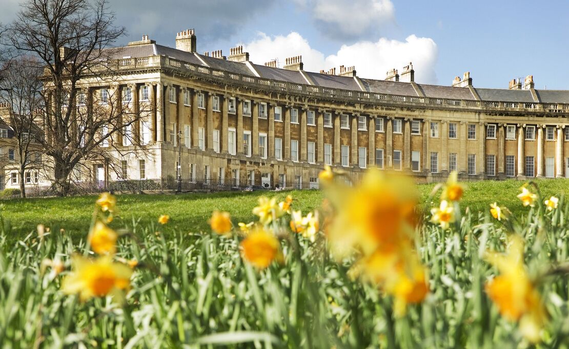 External view of regency style curved row of buildings with a field of blurred out daffodils in the foreground