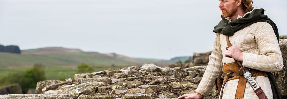 actor in front of Hadrian's wall