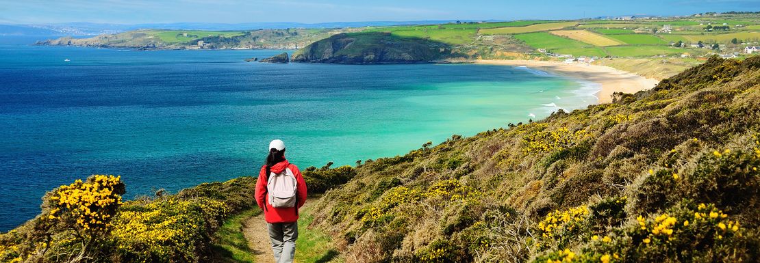 A person on a footpath on the coastal path near sea towards Praa Sands in Cornwall