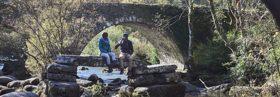 Couple sitting on a stone by a stream in Dartmoor Devon