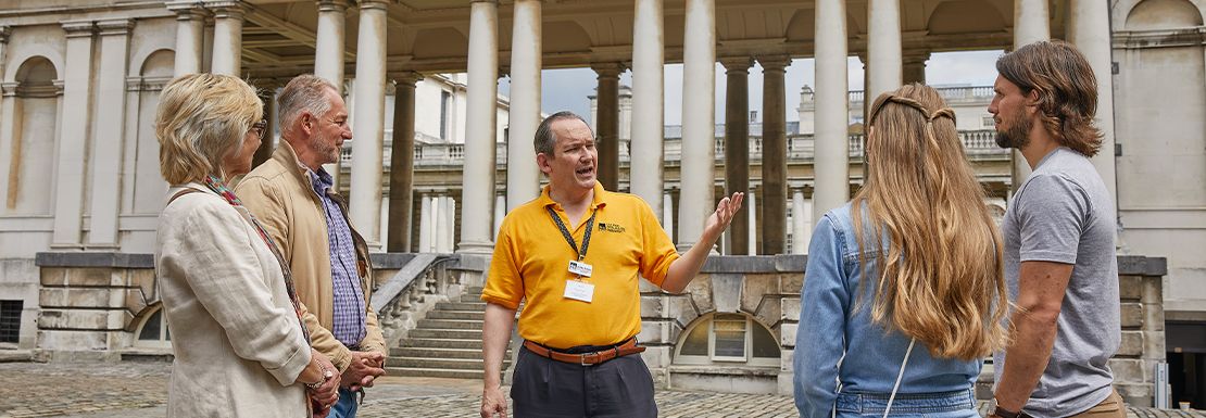 A tour guide helpfully informs visitors about the Old Royal Naval College