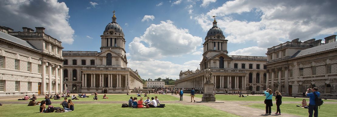 Visitors rest outside on the lawn of the Old Royal Naval College