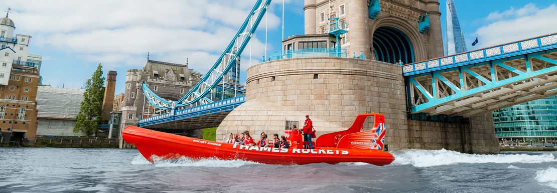 A speedboat travels under Tower Bridge on a sunny day