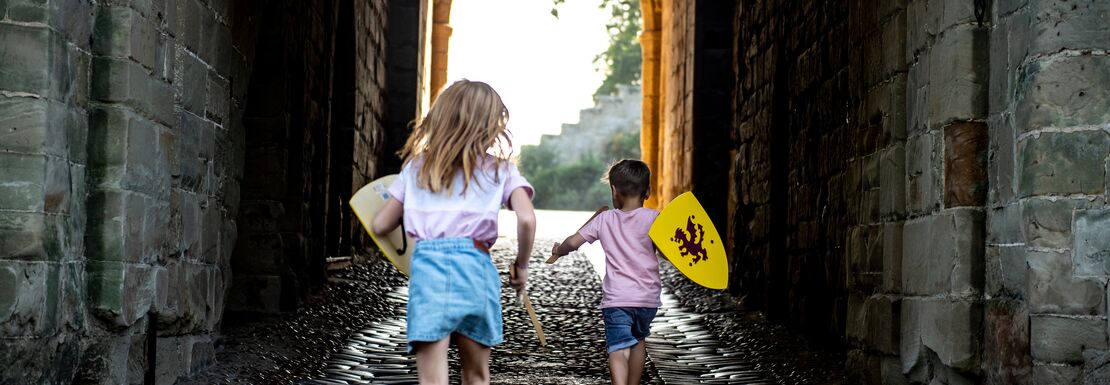 Two young girls stand in a bricked entrance to Warwick Castle