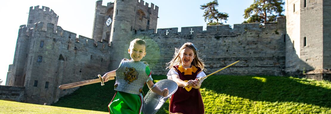 Two girls run, laugh and play with Warwick Castle in the background
