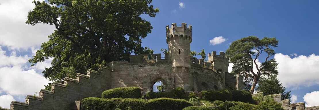A section of Warwick Castle is up on a hill on a sunny day