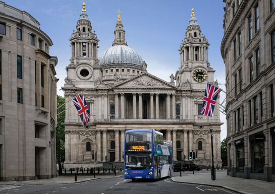 A Golden Tours tourbus turns the corner in front of St Paul's Cathedral with Union Jack flags lining the street
