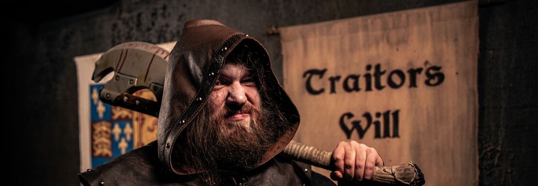 A scary executioner stands next to a sign saying traitors will be executed