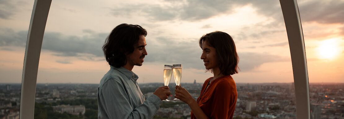 A man and a woman drinking champagne in the London Eye during sunset