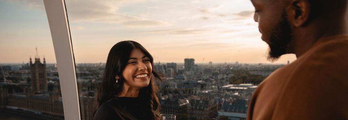 A woman and a man drinking champagne in the London eye pod